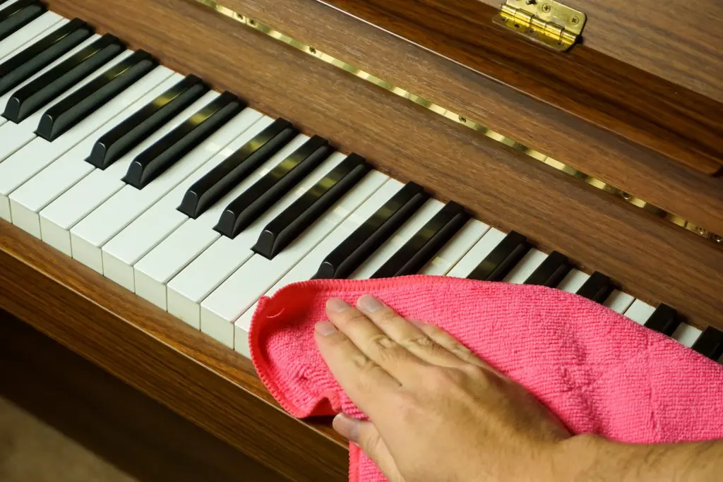 woman cleaning piano keys with a cloth